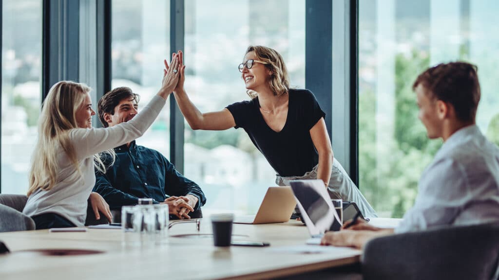 team members celebrate success in a modern conference room, fostering collaboration and enthusiasm.
